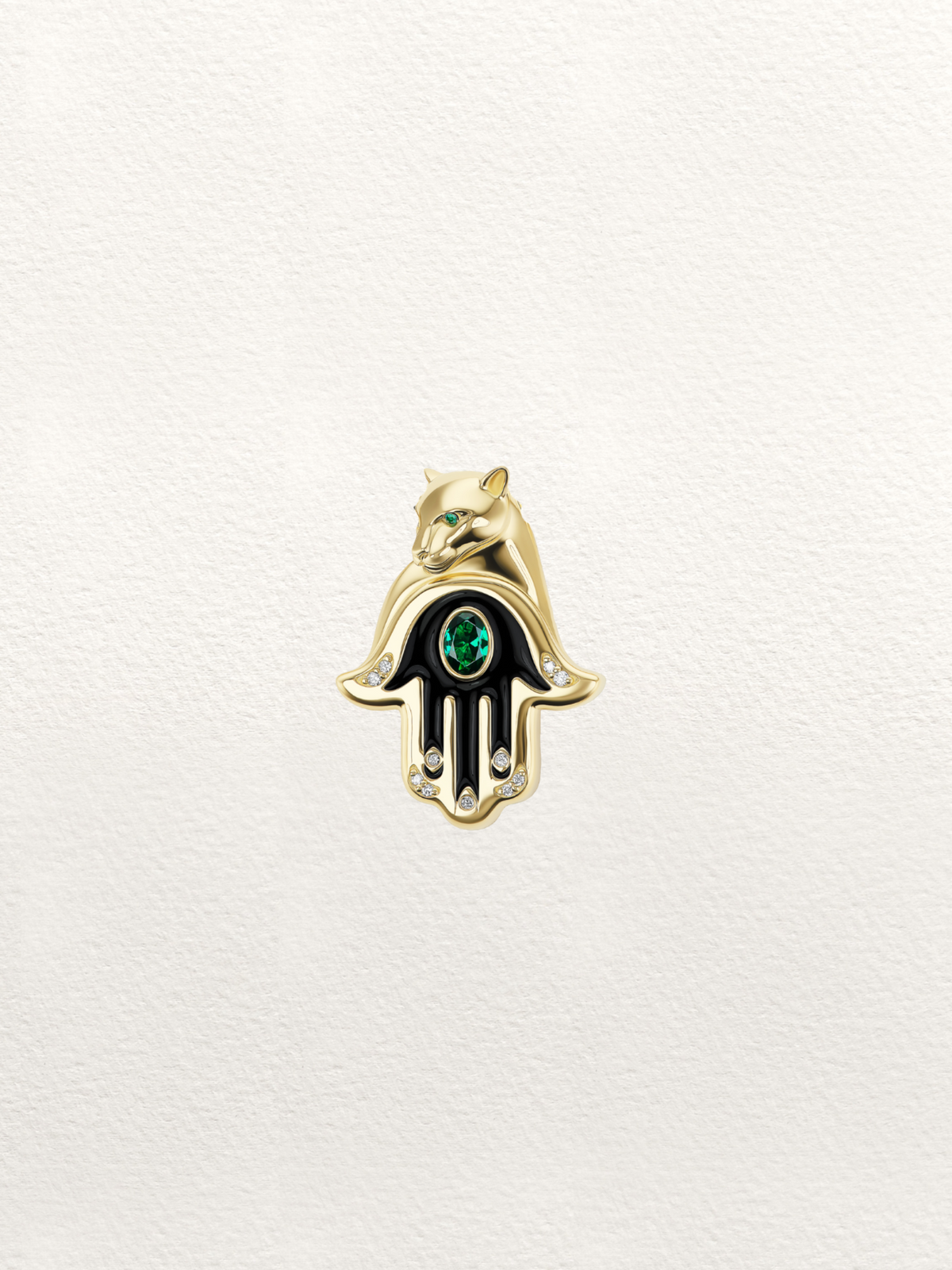 A small gold Hamsa hand charm or brooch with a green oval stone in the center, displayed on a textured off-white background.